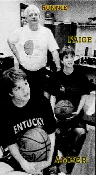 Image of the Guffey family of the Clinton County Lady Bulldogs high school girls basketball team of Kentucky. Identical twin sisters, Amber Guffey (on the left), Paige Guffey, on the right, both holding basketballs in the coaches room, their coach (and father) Ronnie Guffey standing behind them. From the Lexington Herald-Leader, Lexington, Kentucky, February 1, 2005.