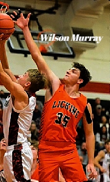 Image of boys basketball player, Wilson Murray, Licking High School (Missouri) shown in red LICKING #35 uniform, attempting to bloxck an opponent's shot up near the basket.